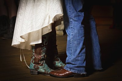 Close-up of man and woman dancing, wearing cowboy boots.