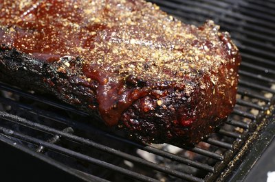 Beef brisket with spices on grill.