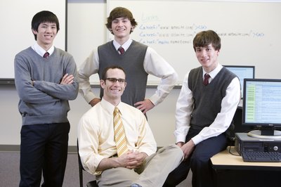 A teacher with three school boys in a computer room.