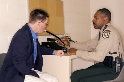 man using breathalyzer in police station