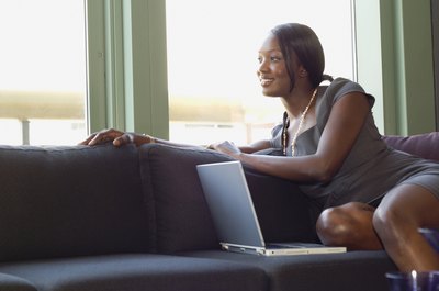 A businesswoman sitting on the couch in front of her laptop.