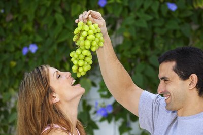 A man feeding his girlfriend some grapes.