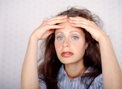 Young woman looking stressed out- hands on her forehead.