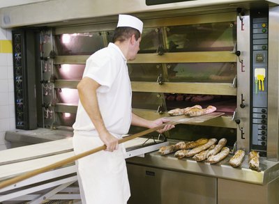 Baker removing bread from oven