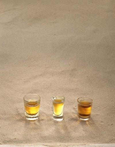 Neat tequila shots on the sand.