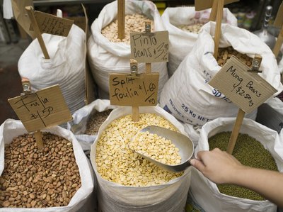 A customer scoops beans at a grocery store.