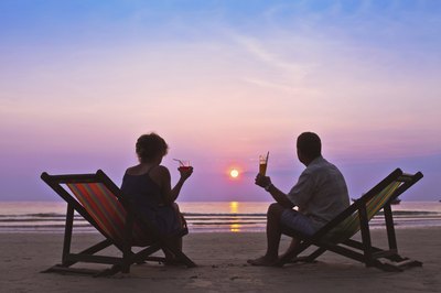 Couple sitting together on beach during sunset.