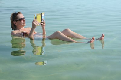 Woman reads a book while floating in the Dead Sea