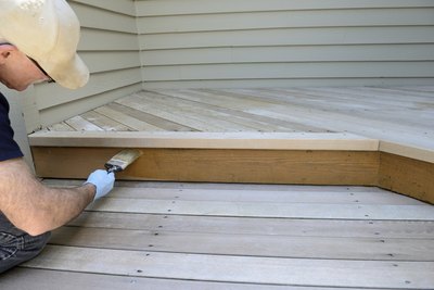 Worker applying sealant to a porch.