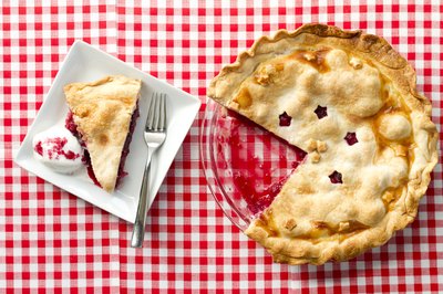 A raspberry pie and single slice on a plate.