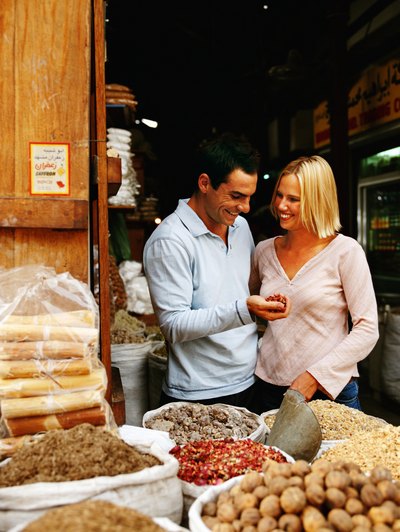 A couple shops for spices at an outdoor market.