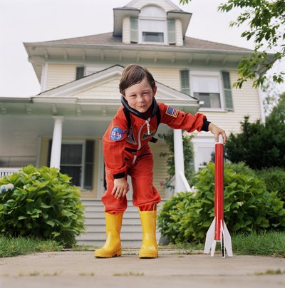 Boy in astronaut outfit holding rocket