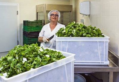 A hospital food worker prepares tossed green salads.