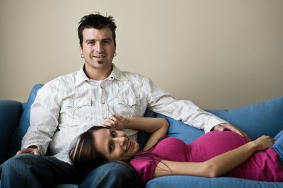 pregnant woman lying on couch with husband