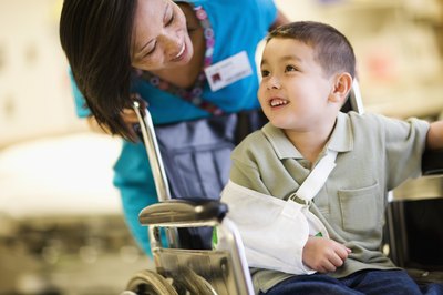 A boy is transported in a wheelchair by a physician.