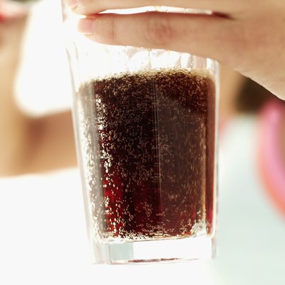 A woman holds a glass of soda.