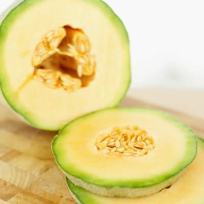 A cantaloupe sliced on a cutting board.