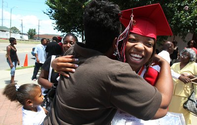 Parent hugging high school graduate