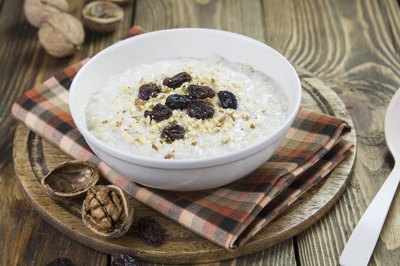 Bowl of oatmeal topped with raisins.