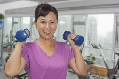 Young woman lifting weights in gym.
