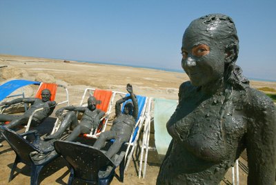 Visitors covered in mineral mud at a Dead Sea spa resort