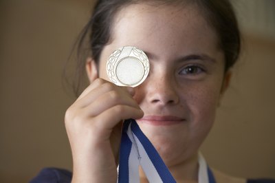 A girl holds a medallion in front of her face.