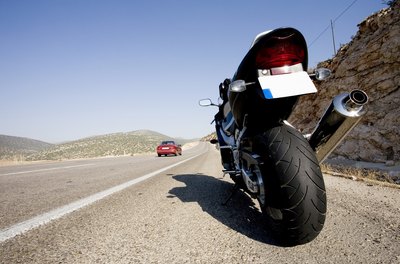 A motorcycle with a wide rear tire is parked on the side of the road.