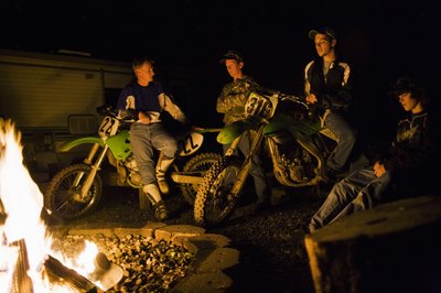 Friends on dirt bikes around camp fire