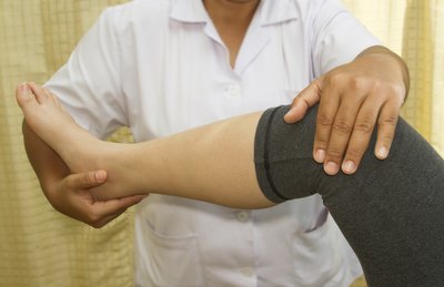 A physician examines a girl's knee.