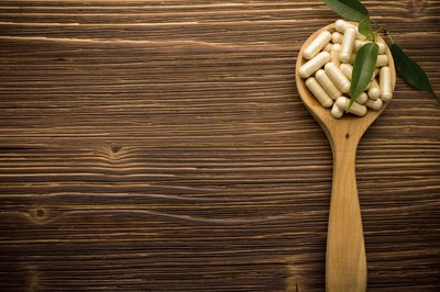 Vitamin supplements on wooden spoon.