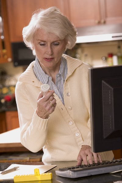 Woman looking at prescription and typing on computer