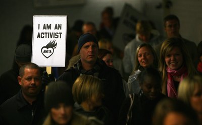A man holding up a paper banner while walking in a parade