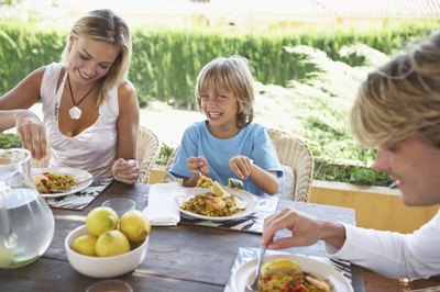 Boy eating at table with parents outdoors