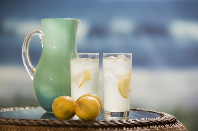 Two glasses of lemonade beside pitcher.