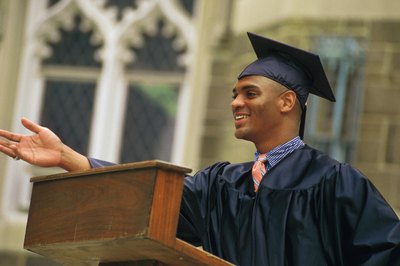 A young man gives a graduation speech at a podium.