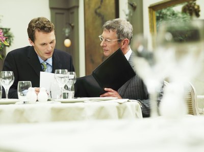 Two employees are having lunch together and looking at the menu.