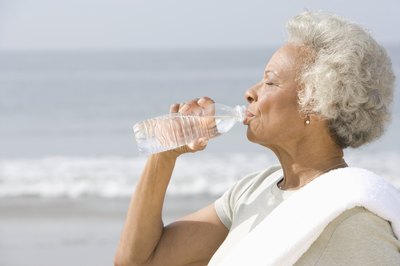 Senior woman drinking distilled water on beach