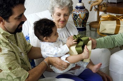 A grandmother opening a gift with her grandson on the sofa.