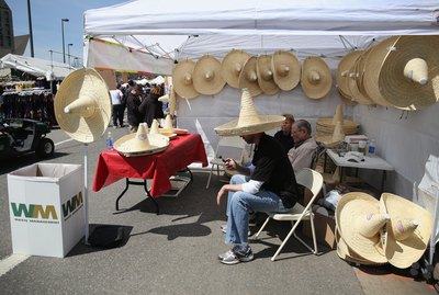 A man selling straw sombreros in a parking lot on Cinco de Mayo.