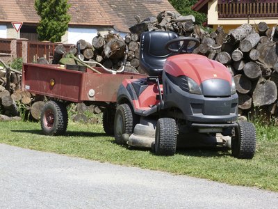 A garden tractor parked in front of a woodpile