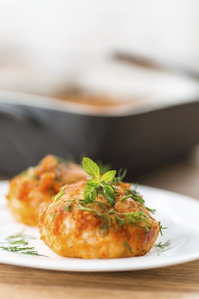 A close-up of meatballs on a dish garnished with fresh herbs.