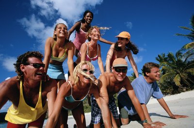 Friends making a human pyramid on the beach.