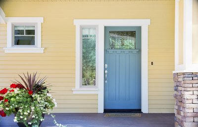 A view from the porch of a Craftsman cottage painted yellow with white trim and blue accents.
