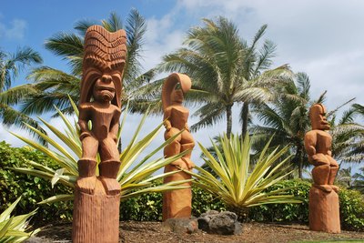 Three Hawaiian Tiki statues on an island.
