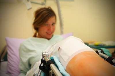 A teenager recovers after knee surgery in a hospital bed.