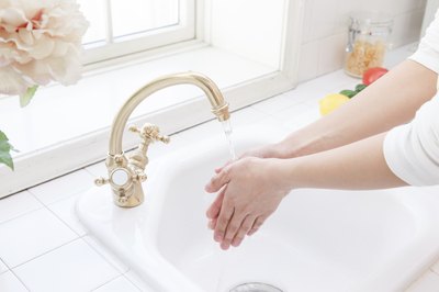 woman washing her hands in kitchen sink