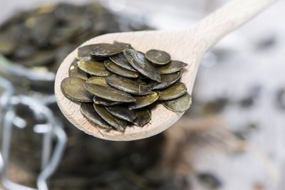 Pumpkin seeds on wooden spoon.