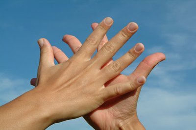 hands in hands against sky, friendship concept image by JoLin from Fotolia.com Using taste deterrent on your hands can prevent your puppy from biting your hands.