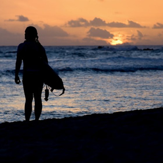 A surfer walks on the beach at sunset