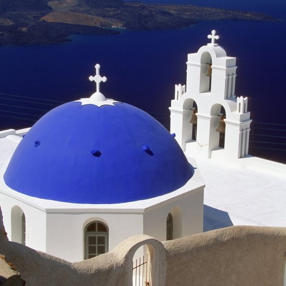 A church dome and bell tower overlooking the coast of Santorini.